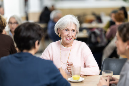 Pleasant positive elderly woman meeting and chatting with family in cozy cafeteriaの写真素材