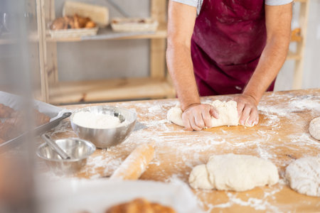 Male baker kneading dough close-up
