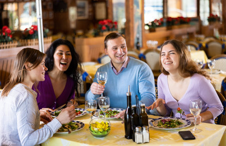 Group of friends enjoying evening meal at restaurant
