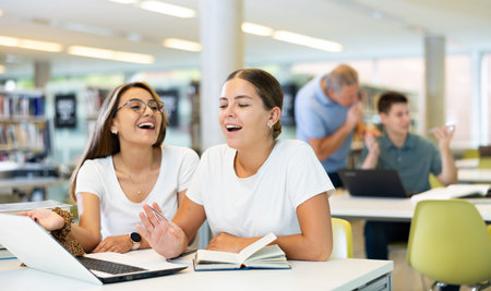 Young female students studying compared to a noisy male in the background