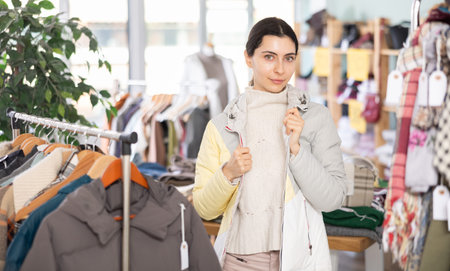 Young woman trying on down jacket in storeの写真素材