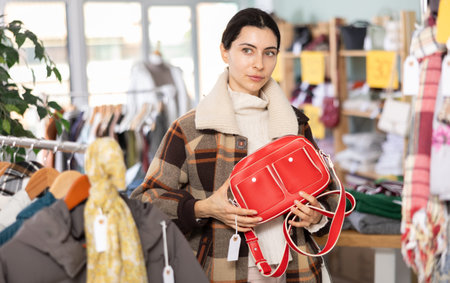 Girl happily chooses fashionable handbag in clothing store