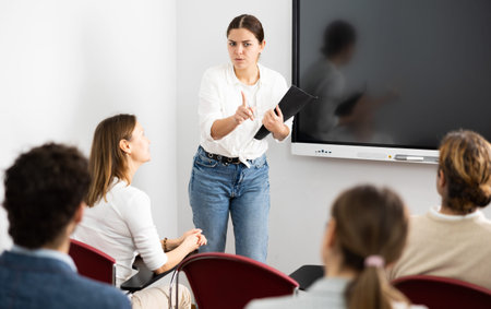 Portrait of young businesswoman standing near interactive board and participating in corporate...