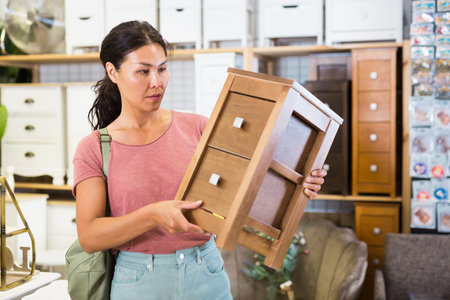 Portrait of woman choosing chest of drawers in furniture storeの写真素材