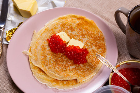 Baked pancakes with red grainy salmon caviar and butter. Traditional Russian holiday dish and...