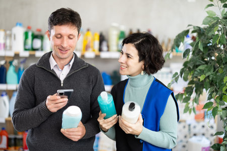 Woman seller help man visitor scan QR code, get information about shower gel in mobile appの写真素材