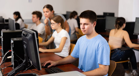 Portrait of interested teenage male student during lesson in computer room of library