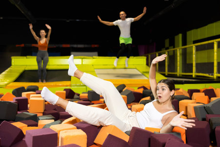 After jumping on trampoline, the girl fell on soft, safe filler cubes