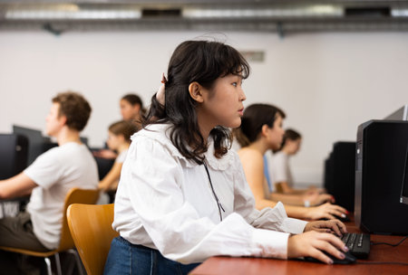 Portrait of diligent asian college girl studying in computer room using computer