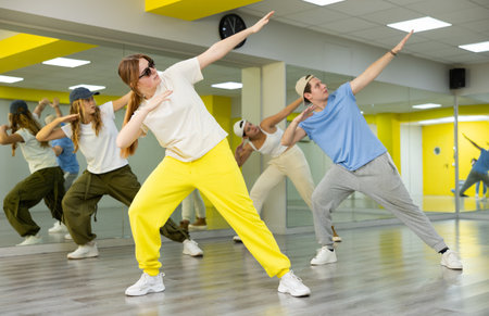 Cool sportive teenagers in casual wear practicing new moves during dance training together in studio