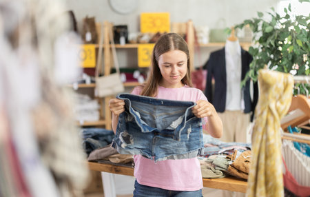 Teenage girl chooses denim shorts in store