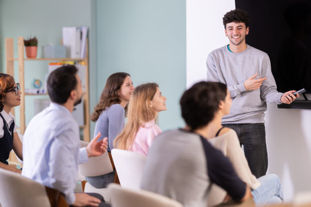 man stands with a remote control in front of students