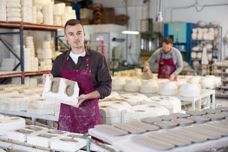 Young man showing poured clay molds