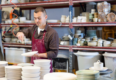 Ceramicist using air blow gun to remove dust from ceramicsの写真素材
