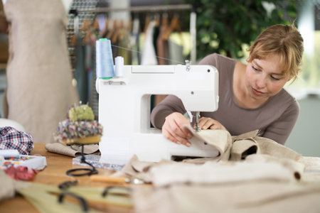 Female clothing designer stitching fabric on sewing machine in studio