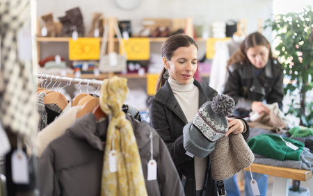 Female shopper chooses a hat in clothing store