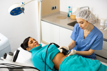 Cosmetologist making ultrasound lifting procedure in abdominal zonesの写真素材