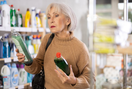 Elderly female customer diligently picking out dishwashing liquidの写真素材