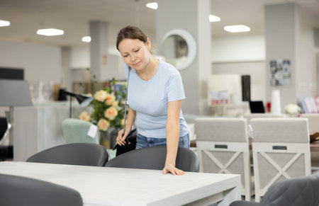 Satisfied woman chooses new modern table in furniture storeの写真素材