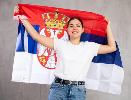 Happy girl stands with flag of Serbia. Isolated on gray backgroundの写真素材