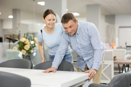 Spouses choose dining table desk in furniture store showroomの写真素材