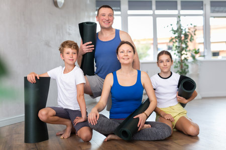 Portrait of happy family of four with mats in their hands after doing yoga in gymの写真素材