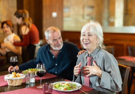 Elderly couple eating and talking in restaurantの写真素材