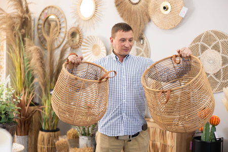 Man looking for functional spacious wicker baskets at storeの写真素材