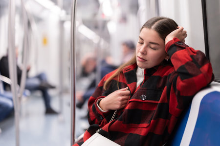 Girl sit and doze in tram car, getting to workの写真素材