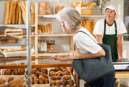 European senior woman look at rack shelf showcase filled with various flour productsの写真素材