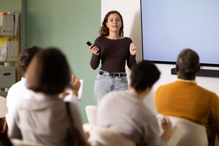 Young woman teacher gives lecture to group in lecture hallの写真素材