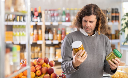 Adult man choosing olives in grocery storeの写真素材