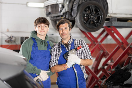 Guy and man mechanics posing in car repair shopの写真素材