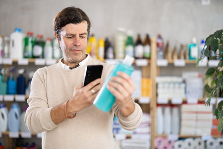 Adult man scanning qr code for shampoo or shower gelの写真素材