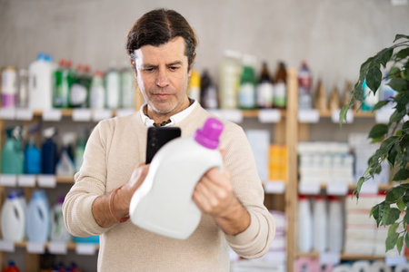 Checking expiration date of detegrent - male shopper scans QR code on label of detegrent using smartphoneの写真素材