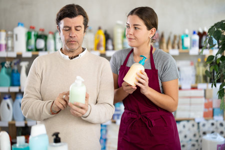 Customer choosing liquid soap with help of young saleswoman in storeの写真素材