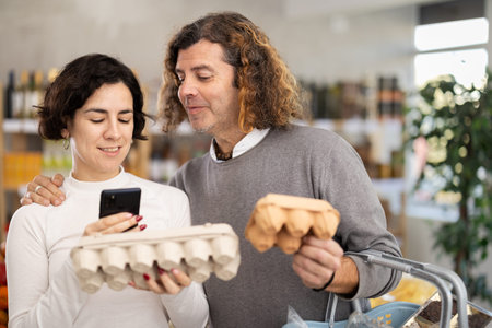 Woman and man scanning eggs in storeの写真素材