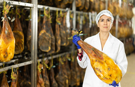 In jamon production shop, woman employee demonstrates final productの写真素材