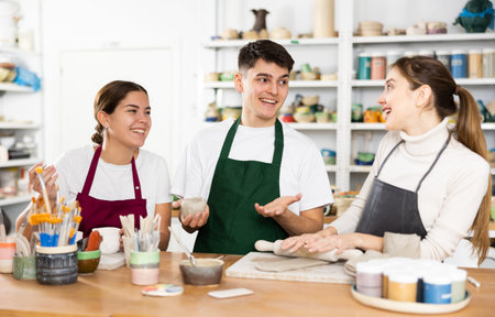 Two young women and young man making pottery