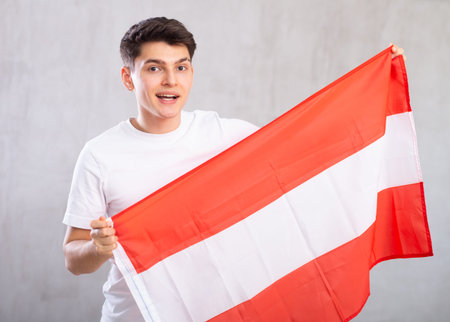 Happy young man holding flag of Austria against unicoloured backgroundの写真素材