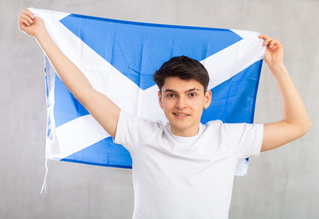 Excited young man with Scotland flag rooting for your favorite teamの写真素材