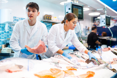 Male seller demonstrates large piece of tuna fillet at fish marketの写真素材