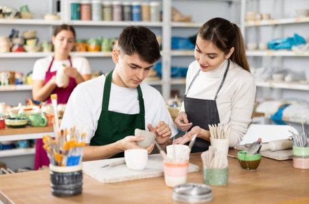 Young man and woman sculpting cups with masterの写真素材