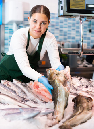 Saleswoman offering fresh fish atlantic cod at seafood shop