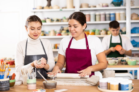 Joyous young women sculpting handmade cups