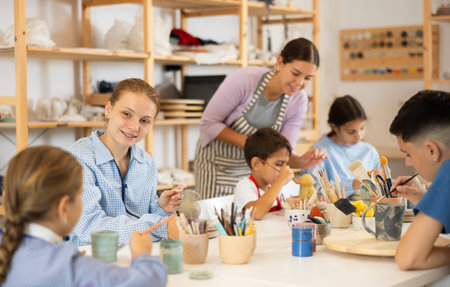 Teenage girl speaking to a circle member while processing ceramic itemsの写真素材