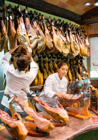 Young woman and man in uniform selling jamonの写真素材