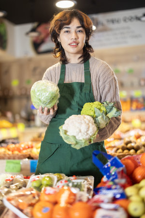 Young female seller offering cauliflower in grocery market