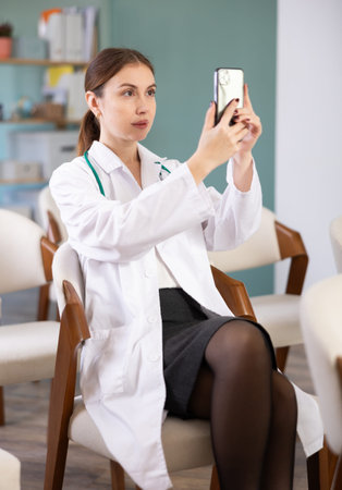 Young woman doctor or medical student scanning QR code with phone