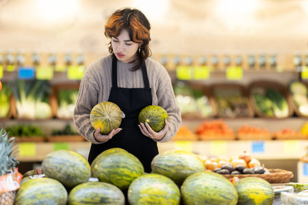Woman employees in uniform holding vegetables in grocery shopの写真素材